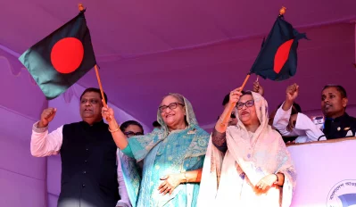 সিলেটে জনসভা মঞ্চে জনতার উদ্দেশে জাতীয় পতাকা নেড়ে অভিবাদ জানান আওয়ামী লীগ সভাপতি শেখ হাসিনা। সঙ্গে ছিলেন ছোট বোন শেখ রেহানা। ইমেজ: সাইফুল ইসলাম কল্লোল